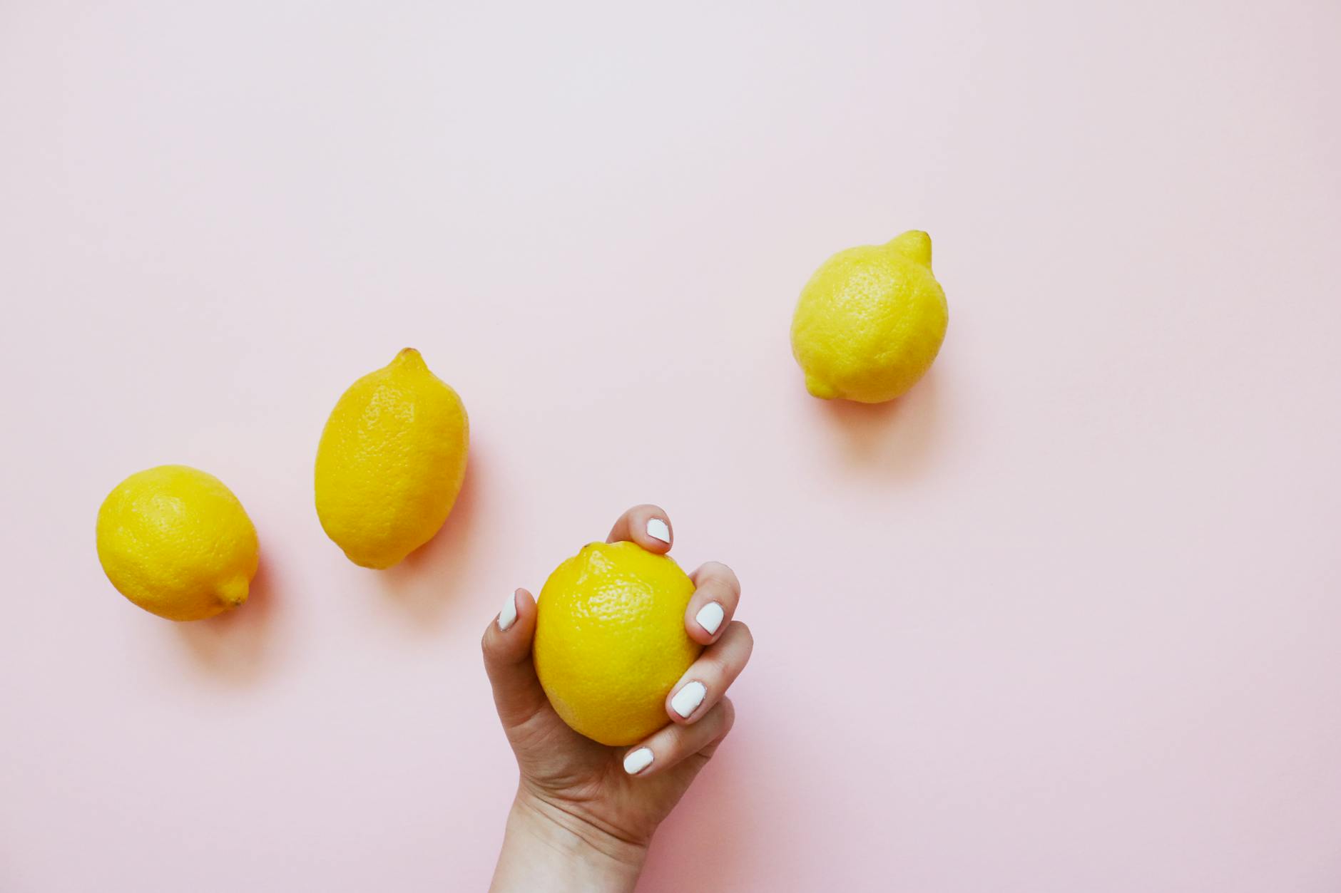 A hand holding a fresh lemon on a soft pink background, symbolizing openness and intimate conversation
