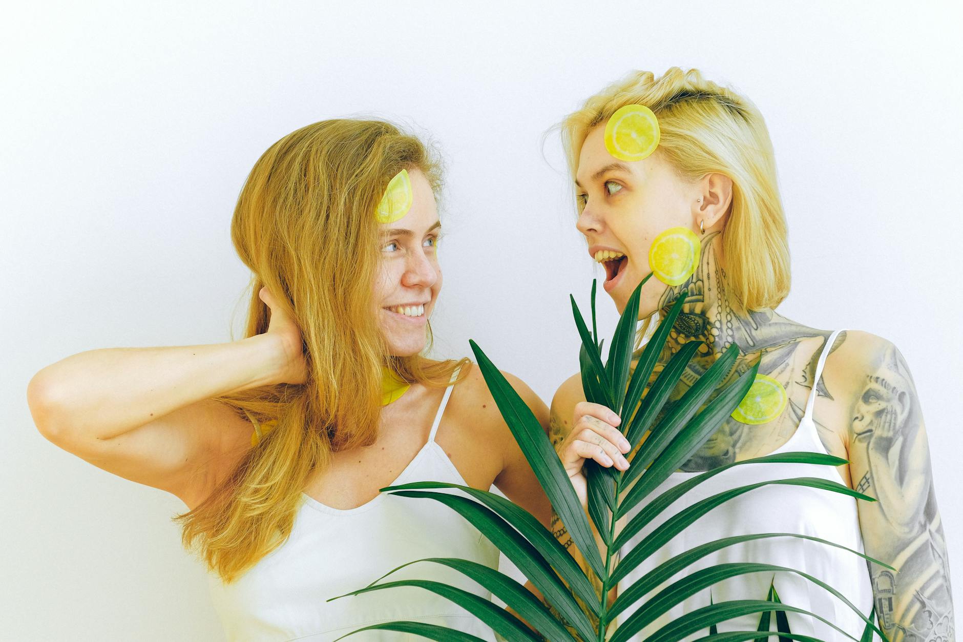 Two women laughing together indoors with fresh lemons and plants, expressing warmth and openness.