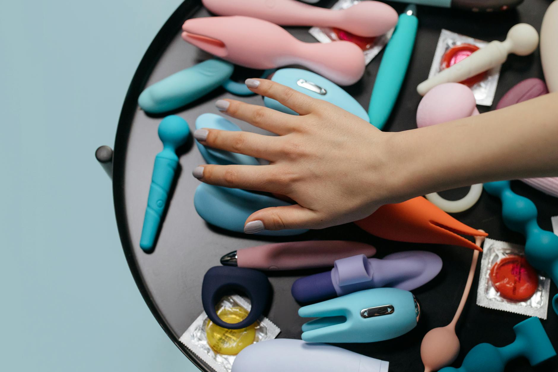 Woman holding blue and pink silicone clitoral vibrators