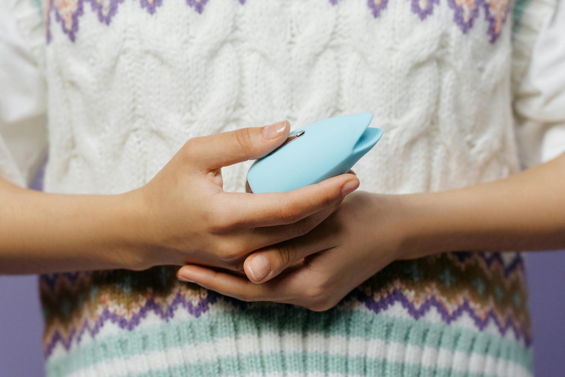 A hand holding a fresh lemon on a soft pink background, symbolizing natural sensitivity and the tactile nature of lemon vibrator design.