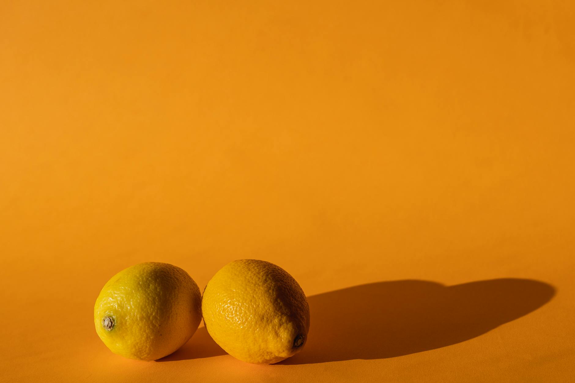 A hand holding a lemon against a bright yellow background, representing fresh sensation and renewed desire